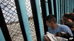 Grupa ljudi kod zida podignutog kod Tihuane na meksičko-američkoj granici