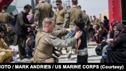 Di Bandara Internasional Hamid Karzai di Kabul pada 20 Agustus 2021 terlihat seorang Marinir AS memberikan air bersih kepada seorang anak selama proses evakuasi. (Foto: AFP/Mark Andries/Korps Marinir AS)