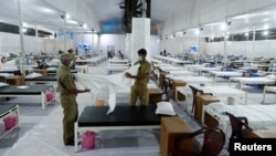 印度工人在孟买新近为新冠病毒感染者修建的隔离设施里为病人准备床铺。（2020年6月22日）