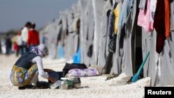 FILE - A Kurdish refugee woman from the Syrian town of Kobani washes dishes at a refugee camp in the border town of Suruc, Sanliurfa province, Turkey, Nov. 11, 2014. 