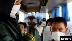 一名中国医务人员在高速公路上的检查站为一名长途客车上的旅客量体温。（2003年5月10日）