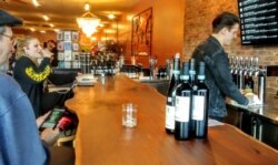 Davis Wills, a manager at UnWined, pours a beer for a customer. (Deborah Block/VOA)