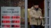FILE - A man leaves a bank displaying currency exchange rates in Moscow, Dec. 20, 2024. 