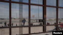 Para migran berlari menuju gerbang di dinding perbatasan setelah diizinkan masuk oleh Garda Nasional Texas, di El Paso, Texas, 20 Maret 2024. (Foto: Justin Hamel/Reuters)