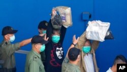Aktivis pro-demokrasi Leung Kwok-hung, yang dikenal sebagai "Rambut Panjang," kiri, dan Lee Cheuk-Yan mengangkat tangan saat mereka dikawal oleh petugas Layanan Pemasyarakatan ke sebuah van penjara untuk pengadilan di Hong Kong, 28 Mei 2021. (Foto: AP)