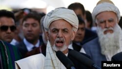 FILE - Afghanistan's President Ashraf Ghani (C) talks with the media after Eid al-Adha prayers at the presidential palace in Kabul.