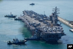 Kapal induk AS USS Ronald Reagan dikawal saat tiba di Busan, Korea Selatan, Jumat, 23 September 2022. (Foto: AP)