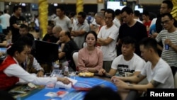 រូបឯកសារ៖ ភ្ញៀវ​ជនជាតិ​ចិន អង្គុយ​នៅ​ជុំវិញ​តុ​លេងល្បែង​មួយ​នៅ​រាត្រី​នៃ​ការចាប់​បើក​ដំណើរការ​កាស៊ីណូ DV នៅ​ក្រុងព្រះសីហនុ ប្រទេស​កម្ពុជា កាលពី​ថ្ងៃទី១៨ ខែឧសភា ឆ្នាំ២០១៩។