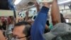 Para penumpang, sebagian besar mengenakan masker, tampak berdesakan di dalam kereta di Jakarta, hari Senin (23/3) di tengah perebakan virus corona.