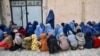 Afghan women and children wait to receive food aid from a local charity during the holy fasting month of Ramadan in Mazar-i-Sharif on March 5, 2025.