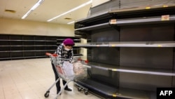 2020年2月6日戴着防护口罩的购物者在香港超市被全部卖空的货架旁