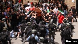 Polisi anti huru-hara Israel memukuli para pelayat yang mengantarkan jenazah wartawan Al Jazeera Shireen Abu Akleh pada pemakaman di Yerusalem Jumat (13/5). Abu Akleh tewas terbunuh saat meliput serangan pasukan Israel di Jenin, Tepi Barat. 