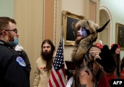 Pendukung Presiden AS Donald Trump, termasuk Jake Angeli (kanan), seorang pendukung QAnon yang dikenal dengan wajah dicat dan topi bertanduknya, memprotes di Gedung Capitol pada 6 Januari 2021, di Washington, DC. (Foto: AFP)