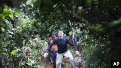 Jurnalis Inggris Dom Phillips (kanan) dan seorang pria suku Yanomami, berjalan di desa Maloca Papiu, negara bagian Roraima, Brazil, November 2019. Phillips dilaporkan hilang di bagian terpencil wilayah Amazon Brazil, Senin, 6 Juni 2022. (AP Photo/Joao Laet)