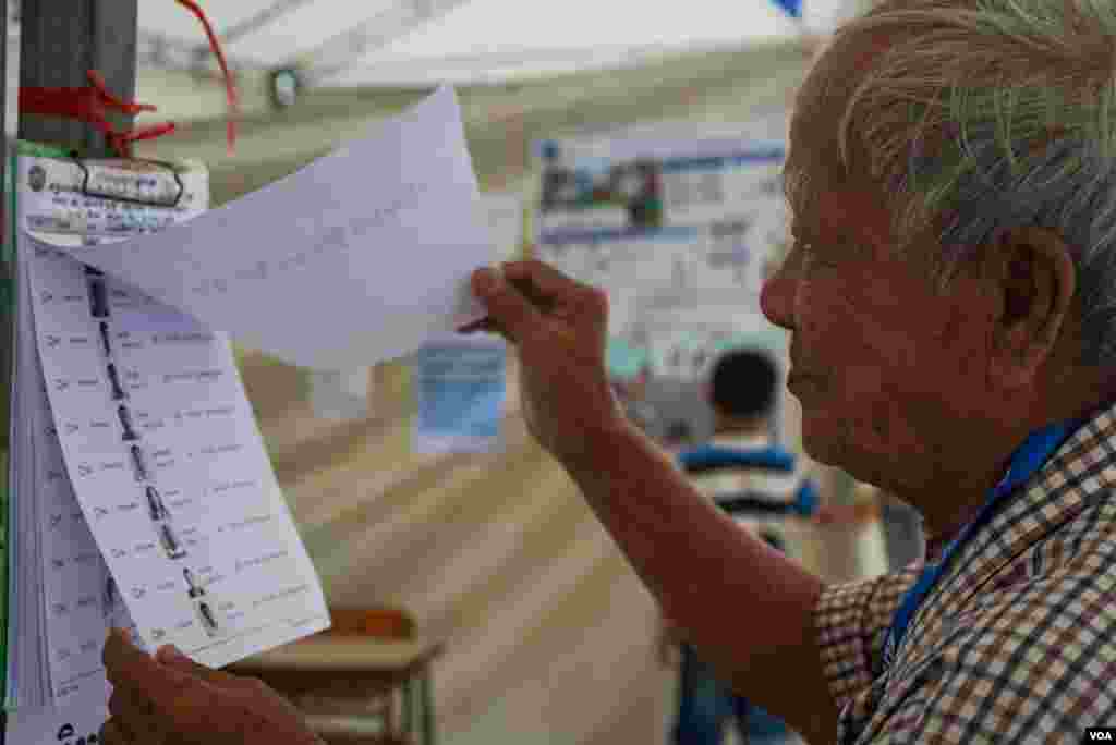 បុរសចំណាស់ម្នាក់ផ្ទៀងផ្ទាត់ឈ្មោះនៅក្នុងបញ្ជីឈ្មោះអ្នកបោះឆ្នោត មួយថ្ងៃមុនថ្ងៃបោះឆ្នោតឃុំសង្កាត់អាណត្តិទី ៥ នៅមណ្ឌលបោះឆ្នោតមួយកន្លែង ក្នុងសង្កាត់ផ្សារកណ្តាលទី ១ ខណ្ឌដូនពេញ រាជធានីភ្នំពេញ ថ្ងៃសៅរ៍ ទី ៤ ខែមិថុនា ឆ្នាំ ២០២២។ (ខាន់ សុគុំមនោ/វីអូអេ)