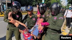 A woman is carried by police officers after security guards broke up a small protest near the Chinese embassy opposing alleged plans to boost Beijing's military presence in the country, in Phnom Penh, Cambodia October 23, 2020. (REUTERS/Heng Mengheang)