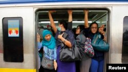 Sejumlah penumpang perempuan berdempetan agar bisa masuk ke dalam kereta yang berangkat dari Stasiun Sudimara, Tanggerang Selatan, pada 3 Juni 2013. (Foto: Reuters/Beawiharta)