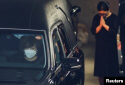 安倍晋三的遗孀昭惠坐在安倍的灵车前座开往寺庙。（2022年7月11日）