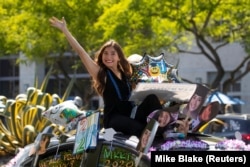 Seorang lulusan California State University San Marcos melakukan selebrasi saat mengikuti parade mobil melintasi kampus di San Marcos, California, AS, 15 Mei 2020. (Foto: REUTERS/Mike Blake)
