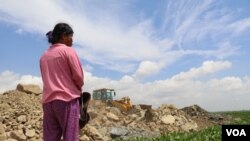 រូបឯកសារ៖ ស្ត្រី​ម្នាក់​កំពុង ឈរ​សម្លឹង​មើល​គ្រឿង​ចក្រ​ចាក់​ថ្ម​ចូល​បឹង​តាមោក ក្នុង​សង្កាត់​សំរោង​ត្បូង​ ​ខណ្ឌ​ព្រែកព្នៅ​ ​រាជ​ធានី​ភ្នំពេញ ថ្ងៃទី​២៧ ខែ​មិថុនា ឆ្នាំ២០២២។​ (ហាន ​ណូយ/វីអូអេ)