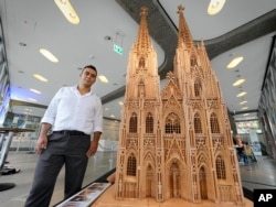Fadel Alkhudr dari Syria berpose di dekat kata heritage Cologne Cathedral di Cologne, Jerman, Senin, 20 Juni 2022. (Foto: AP)
