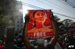 Seorang pengunjuk rasa memegang poster yang menampilkan Aung San Suu Kyi selama demonstrasi menentang kudeta militer di depan Bank Sentral Myanmar di Yangon. (Foto: AFP)