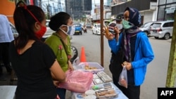 Warga membeli makanan untuk berbuka puasa di hari pertama bulan suci Ramadan di Jakarta, 24 April 2020, di tengah pembatasan sosial berskala besar untuk mencegah penularan virus Covid-19. (Foto: AFP)