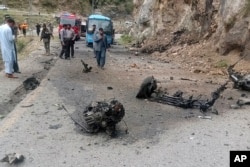 FILE - Police officers examine the site of suicide bombing at a highway in Shangla, district in the Pakistan's Khyber Pakhtunkhwa province, March 26, 2024. The attack killed five Chinese nationals and their Pakistani driver, police and government officials said.
