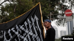 Seorang simpatisan Hizbut Tahrir Indonesia (HTI) membawa bendera saat aksi protes menentang keputusan Presiden Joko Widodo membubarkan HTI, 18 Juli 2017. Kelompok HTI mengatakan mereka tidak mempunyai bendera.