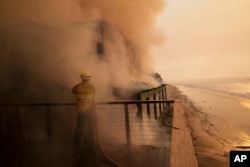 A firefighter protects a beach front property while fighting the Palisades Fire Thursday, Jan. 9, 2025 in Malibu, California.