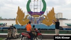 ទេសចរកំពុងថតរូបប្រទីប ខណៈ​ប៉ូលិសកំពុងអង្គុយសម្រាក រាជធានីភ្នំពេញ នាព្រឹកថ្ងៃទី១៣ ខែវិច្ឆិកា ឆ្នាំ២០២៤។ (ចឹង លីលី/វីអូអេ)