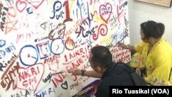 Warga pengunjung ikut melukis mural dalam peringatan 111 tahun Hari Kebangkitan Nasional, Senin (20/5/2019), di Bandung. (VOA/Rio Tuasikal)