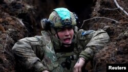 Seorang tentara Ukraina tampak berteriak ketika ia bersembunyi di parit di dekat garis depan pertempuran di Bakhmut, Ukraina, pada 8 Maret 2023. (Foto: Reuters/Lisi Niesner)