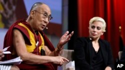 Lady Gaga (kanan) mendengarkan Dalai Lama berbicara pada sesi tanya jawab pada Konferensi Walikota Amerika di Indianapolis, Minggu (26/6). 