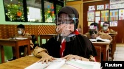 Siswa sekolah dasar yang memakai masker dan pelindung wajah mengikuti kelas, saat sekolah dibuka kembali di tengah pandemi COVID-19, di Jakarta, 7 April 2021. (Foto: REUTERS/Ajeng Dinar Ulfiana)