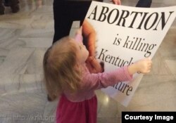一个小孩子手举“堕胎是杀人”的标语牌 （图片来源：Kentucky Right to Life Association）