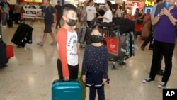 资料照：戴着口罩的儿童从武汉抵达悉尼机场。（2020年1月23日）