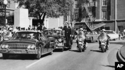 Dalam foto arsip 22 November 1963, terlihat dari jendela depan mobil convertible, President John F. Kennedy memegang kepalanya beberapa saat setelah penembakan. 