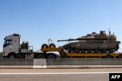 A truck transports an Israeli army main battle tank headed for deployment at the border with Lebanon, along a highway in northern Israel on Sept. 28, 2024.