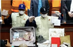 Petugas KPK menunjukkan barang bukti dalam OTT kali ini, berupa yang Rp 1miliar dan sejumlah barang mewah, dalam tangkapan layar. (Foto: VOA/Nurhadi)