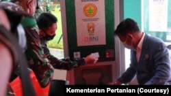Dua orang mencoba menggunakan ATM beras. (Foto: Kementerian Pertanian)