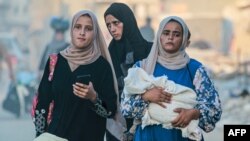 Tiga perempuan tampak berjalan meninggalkan wilayah Khan Younis di Jalur Gaza setelah tentara Israel memerintahkan warga Palestina untuk mengosongkan wilayah tersebut, pada 1 Juli 2024. (Foto: AFP/Bashar Taleb)