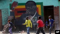 Children play soccer next to a defaced portrait of former Zimbabwean President Robert Mugabe in Harare, Sept, 6 2019.