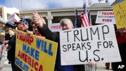 A woman gives a thumbs up as people in a passing car honk as demonstrators in favor of President Donald Trump's executive order banning travel to the U.S. from seven primarily Muslim nations stand across the street from the Tom Bradley International Terminal in Los Angeles, Feb. 4, 2017.