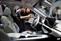 Seorang perempuan mengambil foto interior mobil China Geely Auto di bawah merek elektrik barunya Geometry selama pameran Auto Shanghai 2019 di Shanghai, Selasa, 16 April 2019. (Foto: AP)