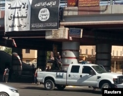 FILE - A fighter from the Islamic State mans an anti-aircraft gun mounted on the rear of a vehicle in Mosul, Iraq, July 16, 2014.