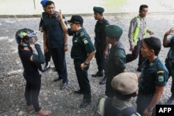 Seorang perempuan Aceh (kiri), yang sedang mengendarai motor, ditahan oleh polisi syariah karena mengenakan celana ketat tanpa hijab di Banda Aceh, ibu kota provinsi Aceh, 7 Mei 2014. (Foto: AFP)