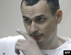 Ukrainian film director Oleg Sentsov looks out from a defendants' cage as he listens to the verdict at a military court in the southern city of Rostov-on-Don, Aug. 25, 2015.