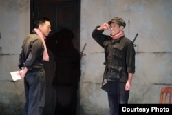 A scene from the 'Cambodian Rock Band' where a Khmer Rouge guard, played by Mose Villarama (Leng) at the S-21 prison, receiving an order from Duch, played by Daisuke Tsuji. (Photo by Jenny Graham, Oregon Shakespeare Festival)