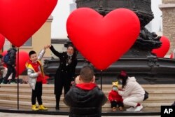 FILE - Families with young children pose for photos in Beijing, Feb. 13, 2021. Struggling with an aging population and a declining birth rate, China is trying to shift its population policies to avert a demographic crisis.